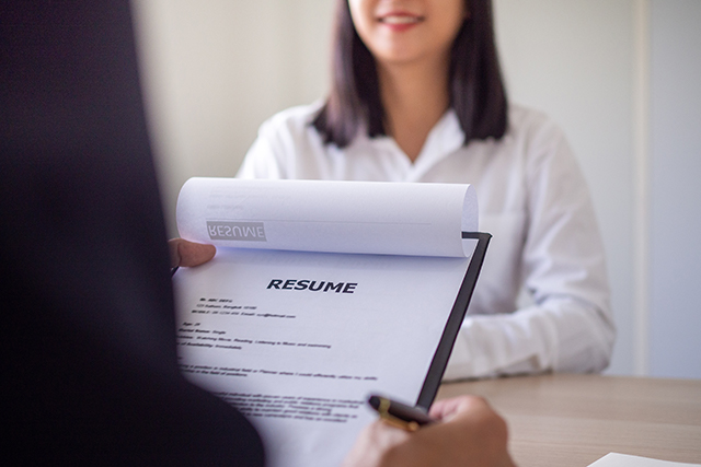 Women in frotn of man holding a resume