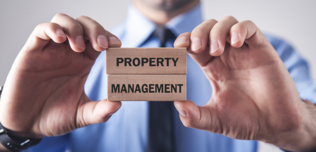 Close up photo of two hands holding wooden blocks that read "property" and "management"