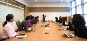 A woman writing on a white board in front of a group of people