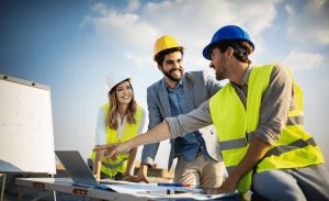 A group of men and women looking at a laptop and charts on a construction site