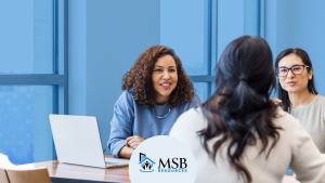Three multifamily professionals talking across a desk during a job interview about a career pivot